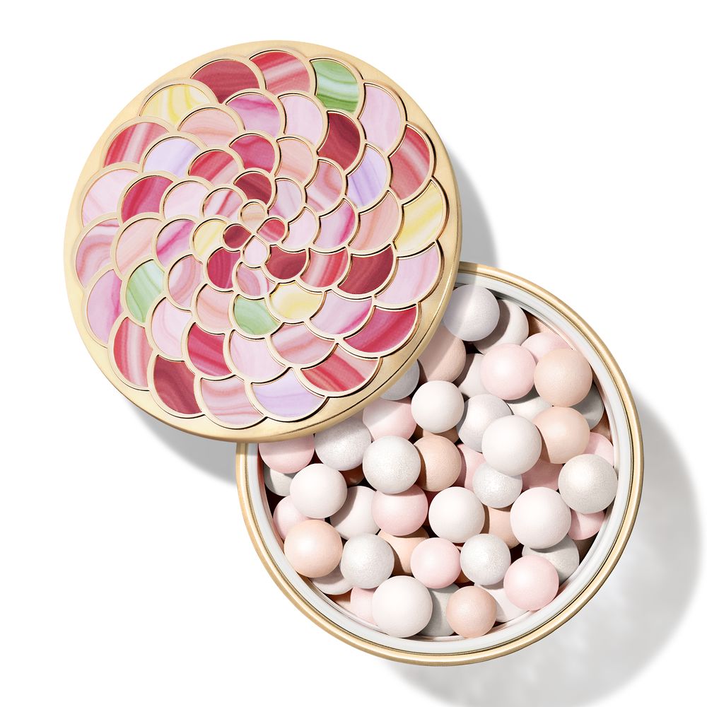 Round metal compact with gold trim holding pink, white, peach, green, yellow powder pearls and floral lid pattern by Guerlain